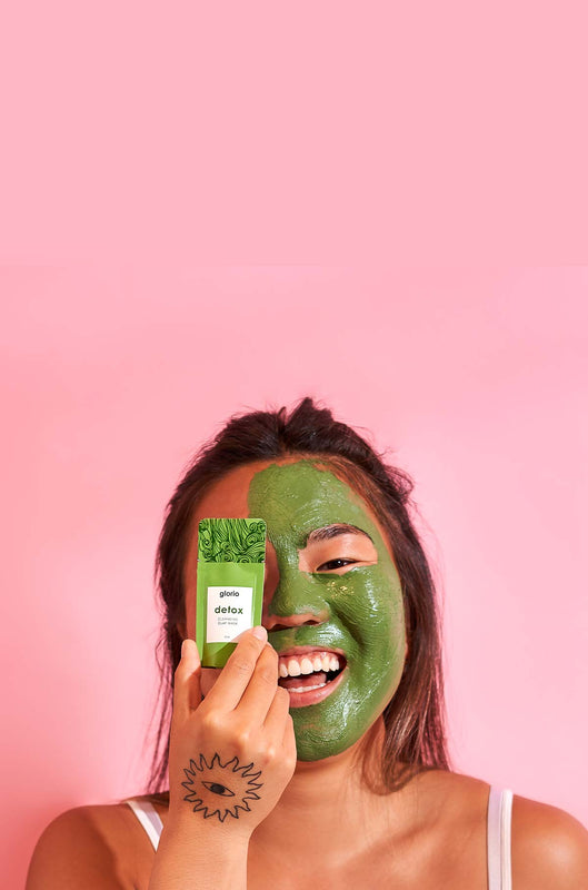 Model holding detox packette with mask applied to face